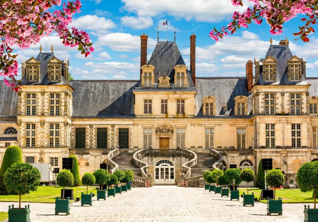 Façade du Château de Fontainebleau au printemps, encadrée de fleurs roses