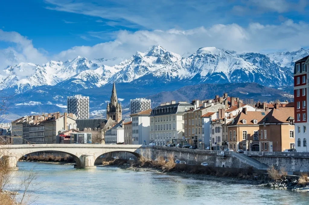 Grenoble au bord de l'Isère, pont de pierre et massifs enneigés en toile de fond