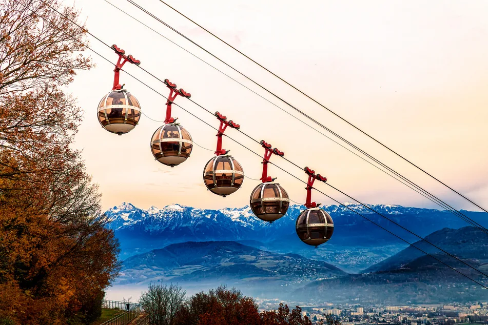 Les bulles du téléphérique de Grenoble-Bastille au crépuscule, face aux sommets enneigés
