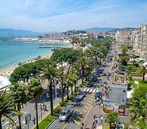 Promenade bordée de palmiers le long de la plage, entre mer et ville animée — Nice
